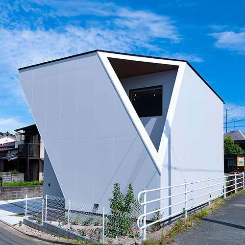 福津市の風景に映える独創的な外観デザインの注文住宅。一級建築士事務所ならではの幾何学的なフォルムと、プライバシーに配慮しつつ空を切り取る大きな三角形の開口部が特徴的な、白を基調としたモダン建築。