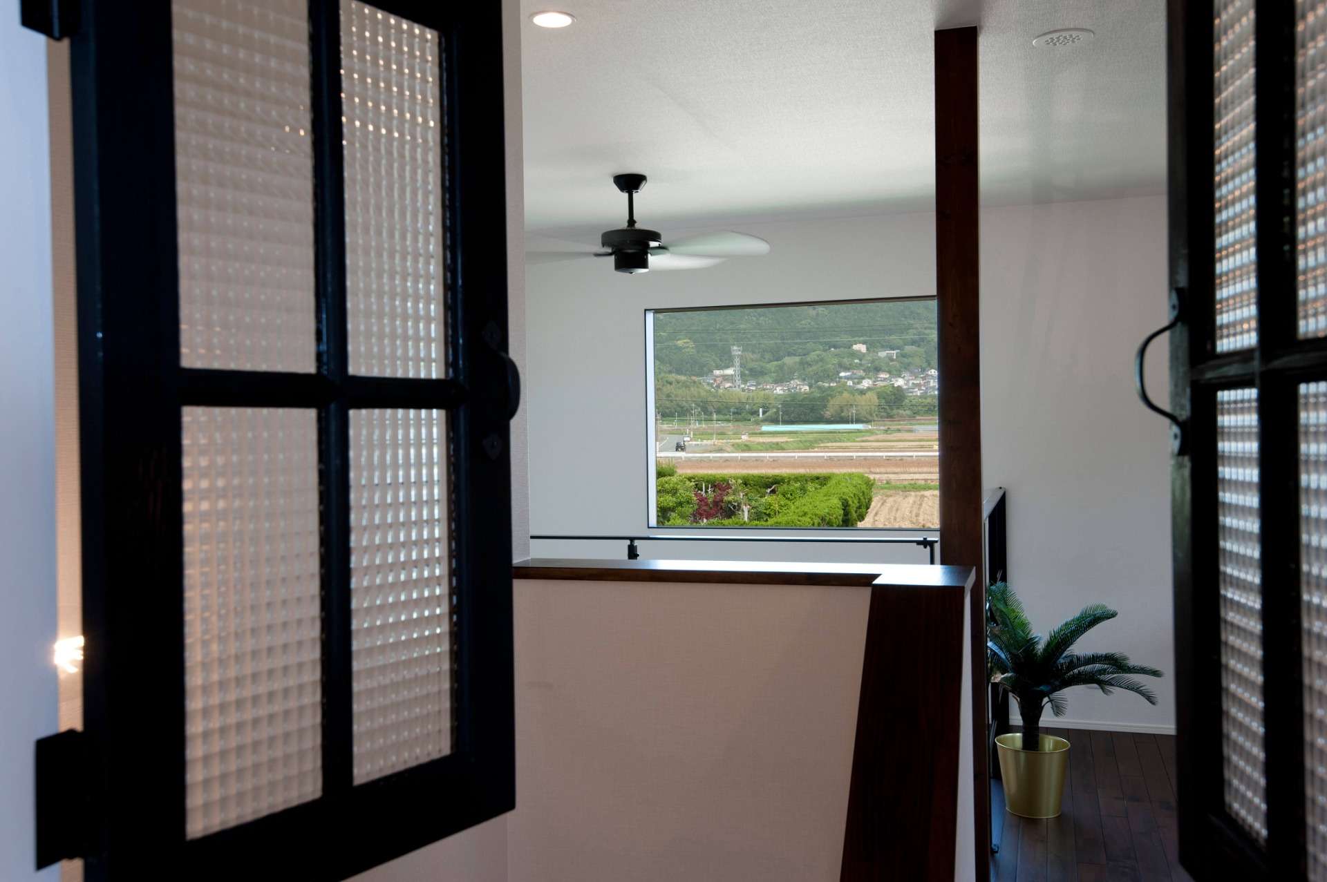 福岡県宗像市の新築内観　階段に設けた窓から吹き抜けのシーリングファンが見える設計