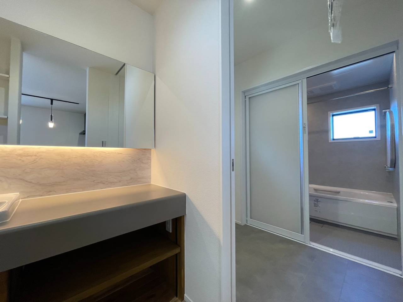 宗像市の新築内観　造作洗面台と浴室　気温が下がりがちな浴室も高性能住宅なら気温の差が少なくヒートショックのリスクが下がります。性能もデザイン、機能性も兼ねた自由設計の家です