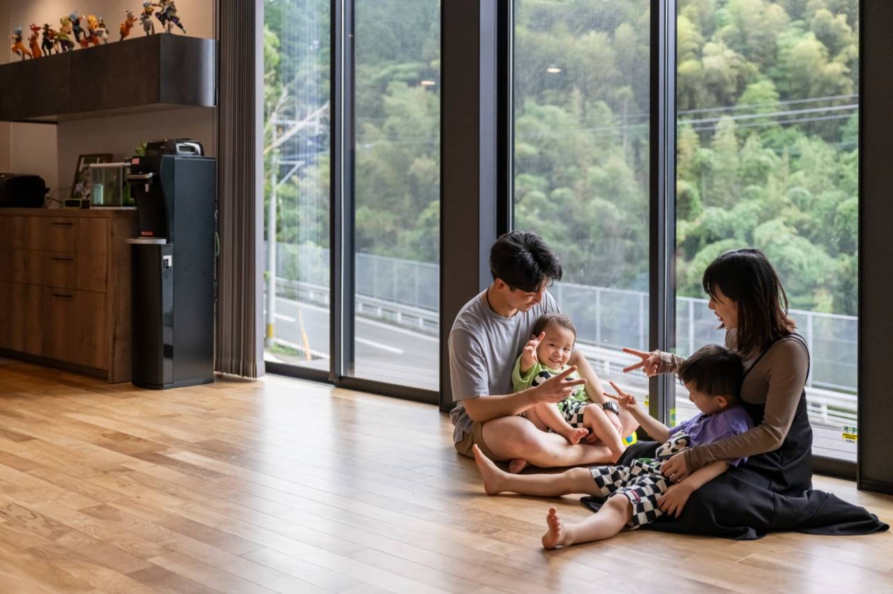 古賀市の注文住宅　多いな窓のある平屋のリビングで親子がくつろぐ様子