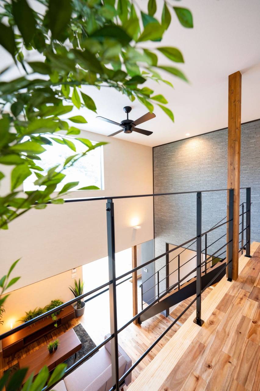 福津市に建つ新築の内観　吹抜けに設けたアイアンの手摺がモダンな印象のピクチャーウインドウから明るい光が差し込んでいる