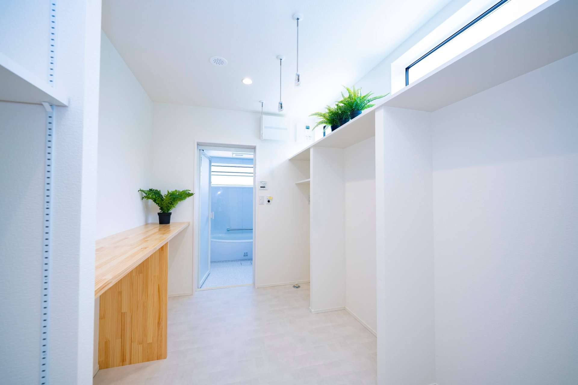 福岡県福津市の新築　浴室から続くランドリースペースとウォークスルークローゼット、ランドリースペースには造作棚がありアイロンを掛けたり洗濯物をたたむことができる