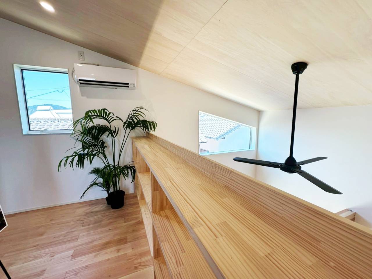 注文住宅の採光・通風計画。木目調の美しい勾配天井に、空気循環を促すシーリングファンと、周囲の視線を遮りつつ光を採り入れる高窓を配置。