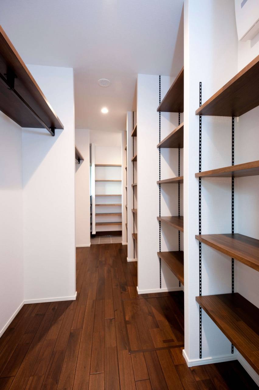 濃いブラウンの床材と木製棚がシックな印象を与える収納空間。ライフスタイルの変化に合わせて棚の高さを自由に変えられる設計。