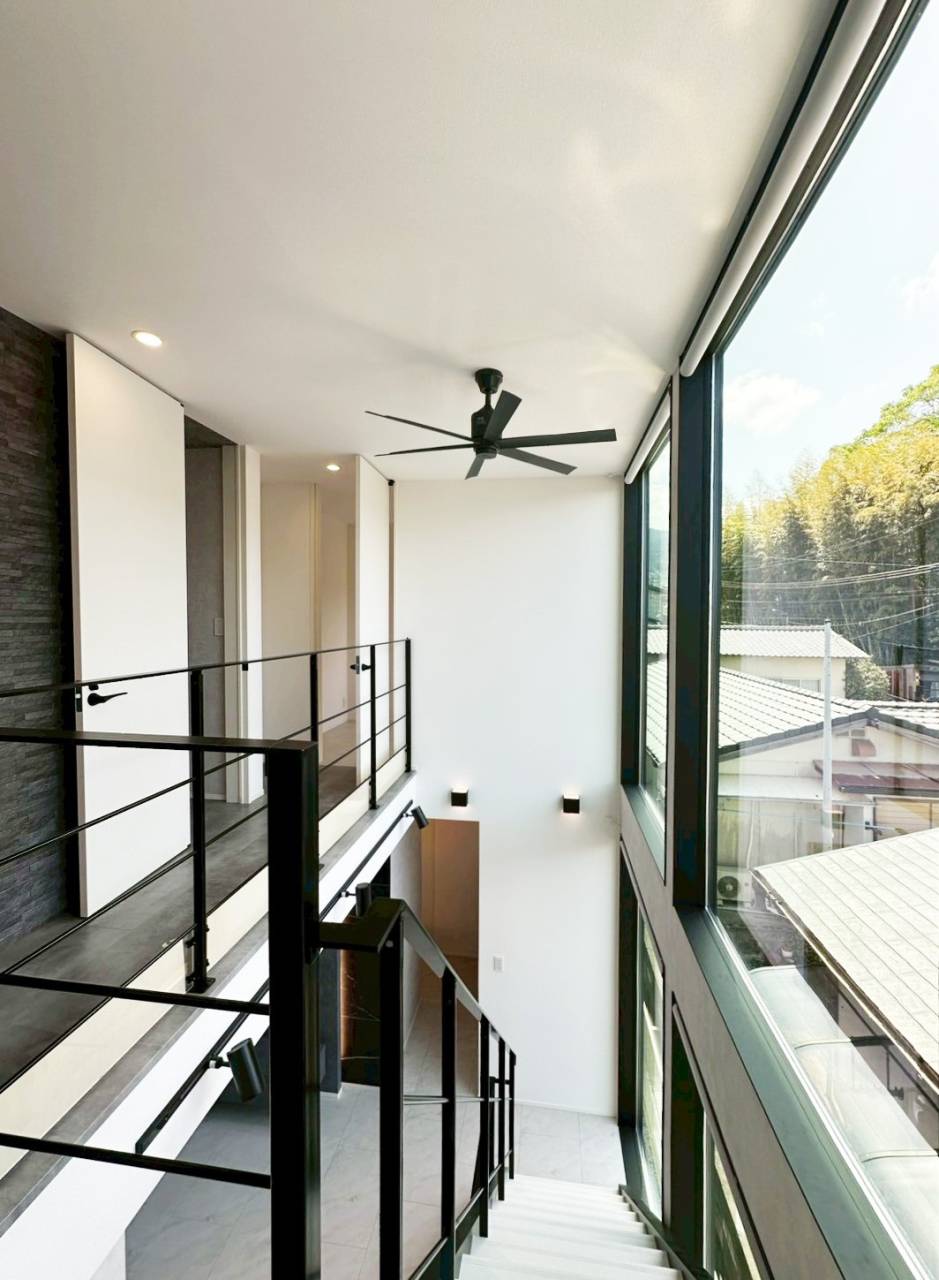 【福岡県福津市】新築　注文住宅の内観　ガラス張りの壁面がある吹抜け階段、アイアン階段がホテルライクな印象の住宅