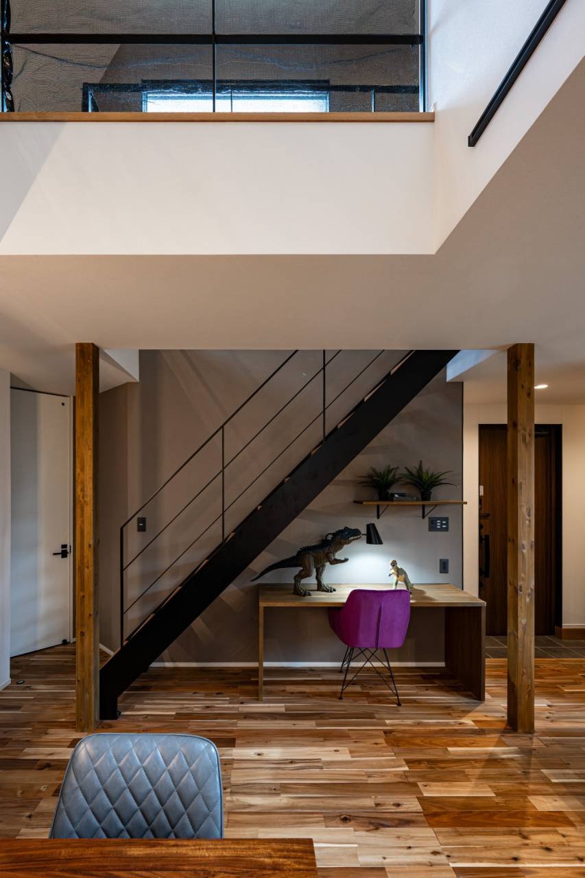 注文住宅の階段下スペースを有効活用したスタディコーナー。無垢材のフローリングと黒のスチール階段が調和する、モダンなワークスペースの設計事例。