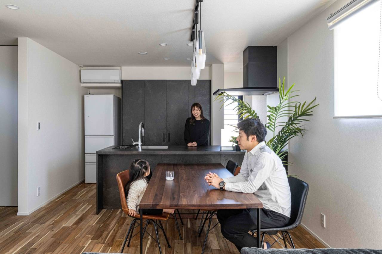 古賀市の注文住宅LDK　リビングと対面キッチンで会話する親子　背面には目隠しのある大容量の収納