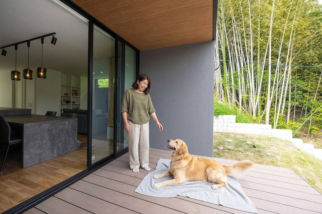 リビングと繋がるうっだデッキで愛犬とくつろぐ女性｜福津市に建つ平屋の注文住宅