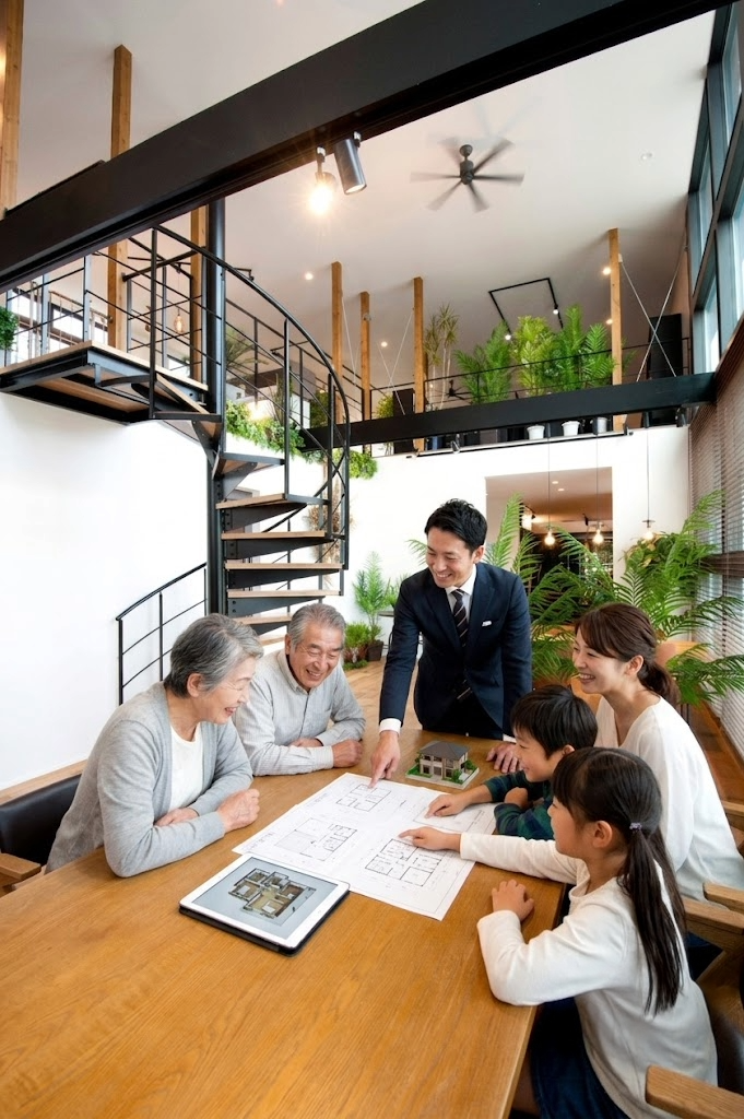 家族全員で住宅の図面を囲み楽しそうに話し合う三世代の風景