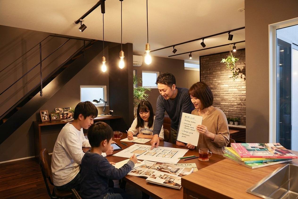リビングのテーブルで家族みんなで理想の間取りや暮らしの希望を話し合う様子
